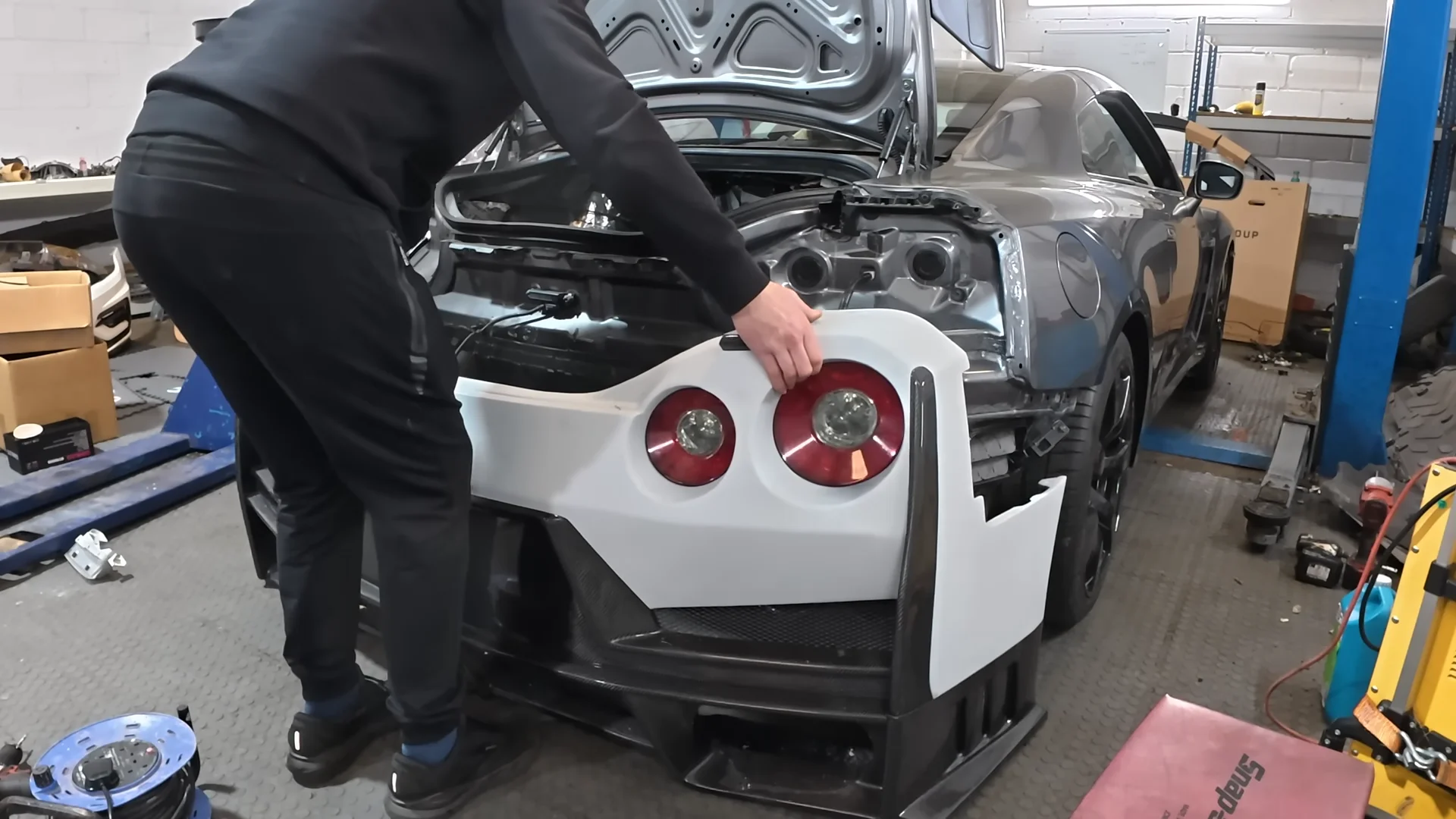A person replacing the rear fascia on a Nissan GT-R
