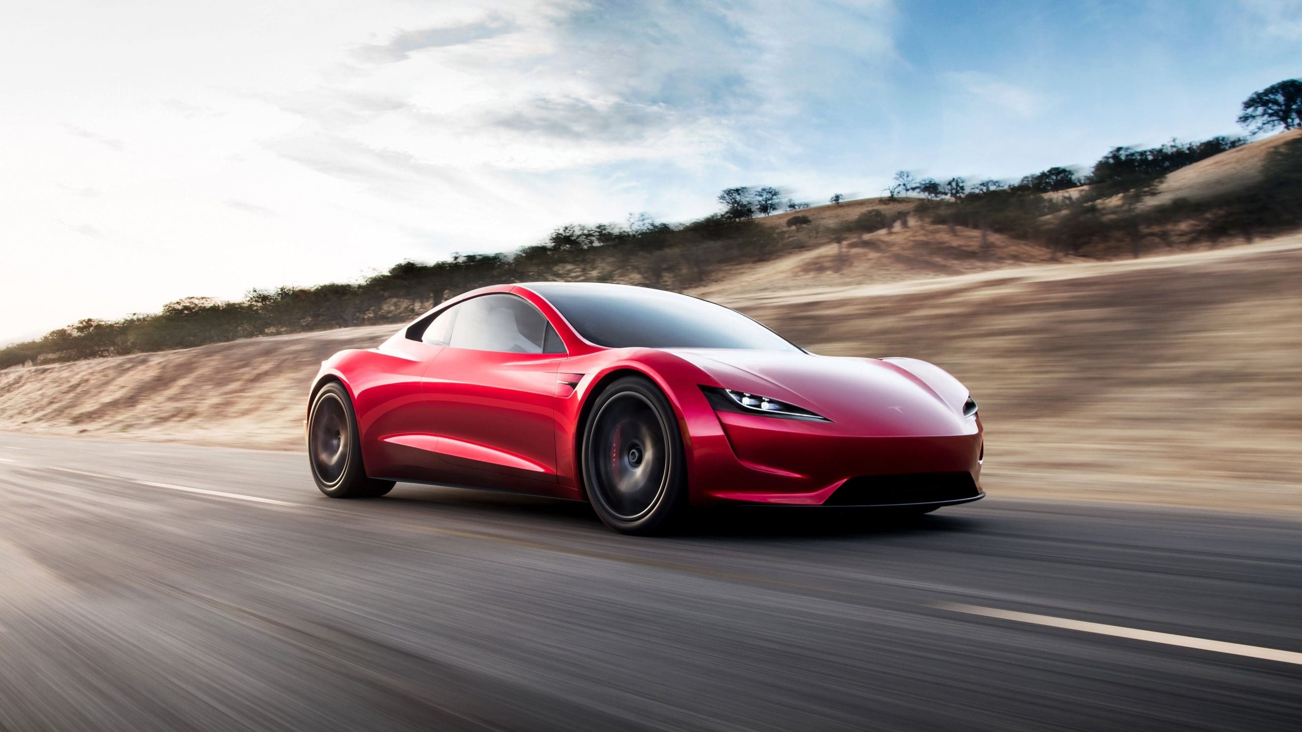 Three-quarter front view of a Tesla's second-generation Roadster sports coupe driving fast on a highway