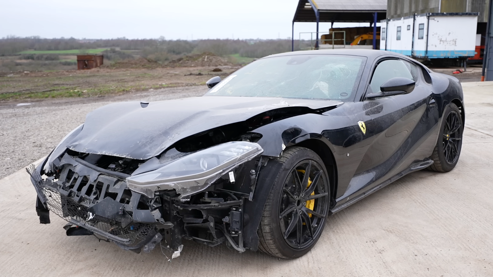 Three-quarter front view of a wrecked black Ferrari 812