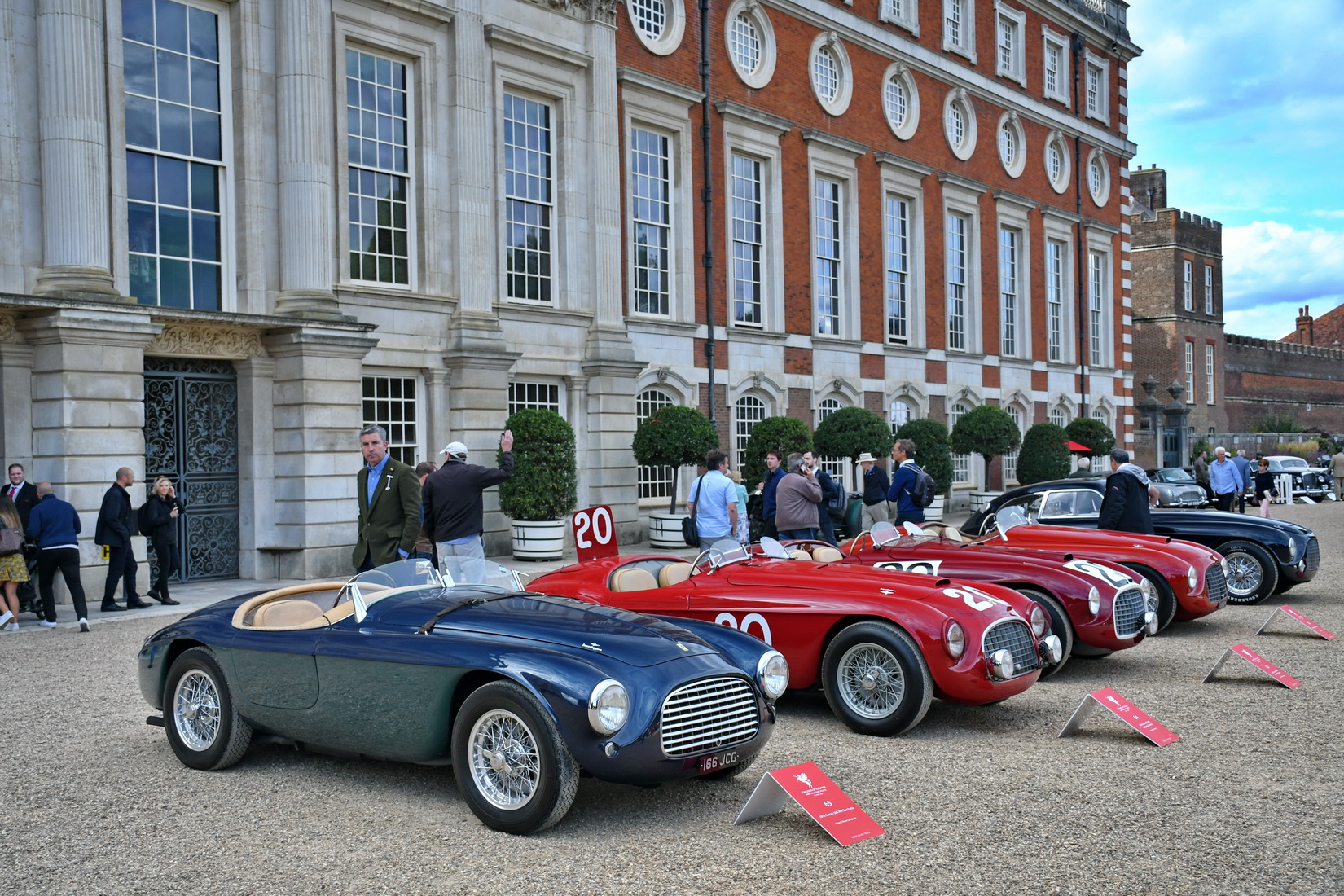 a set of 4 Ferraris 166MM and a 212 Export Berlinetta Touring standing side by side in front of Hampton Court Palace