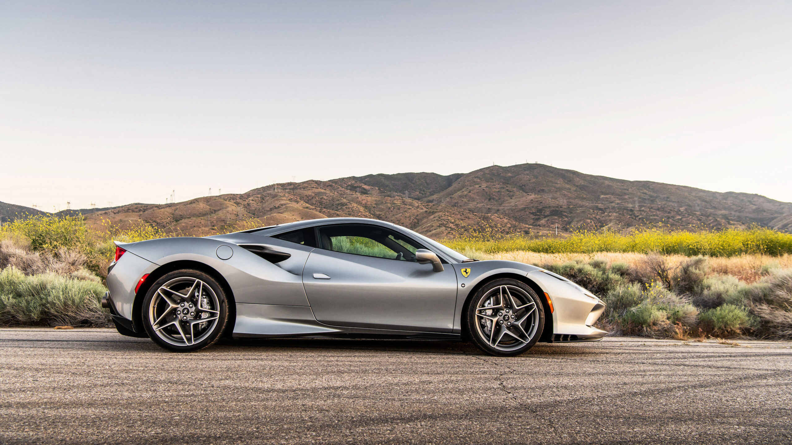 A side view of a silver Ferrari F8 Tributo, in the country.