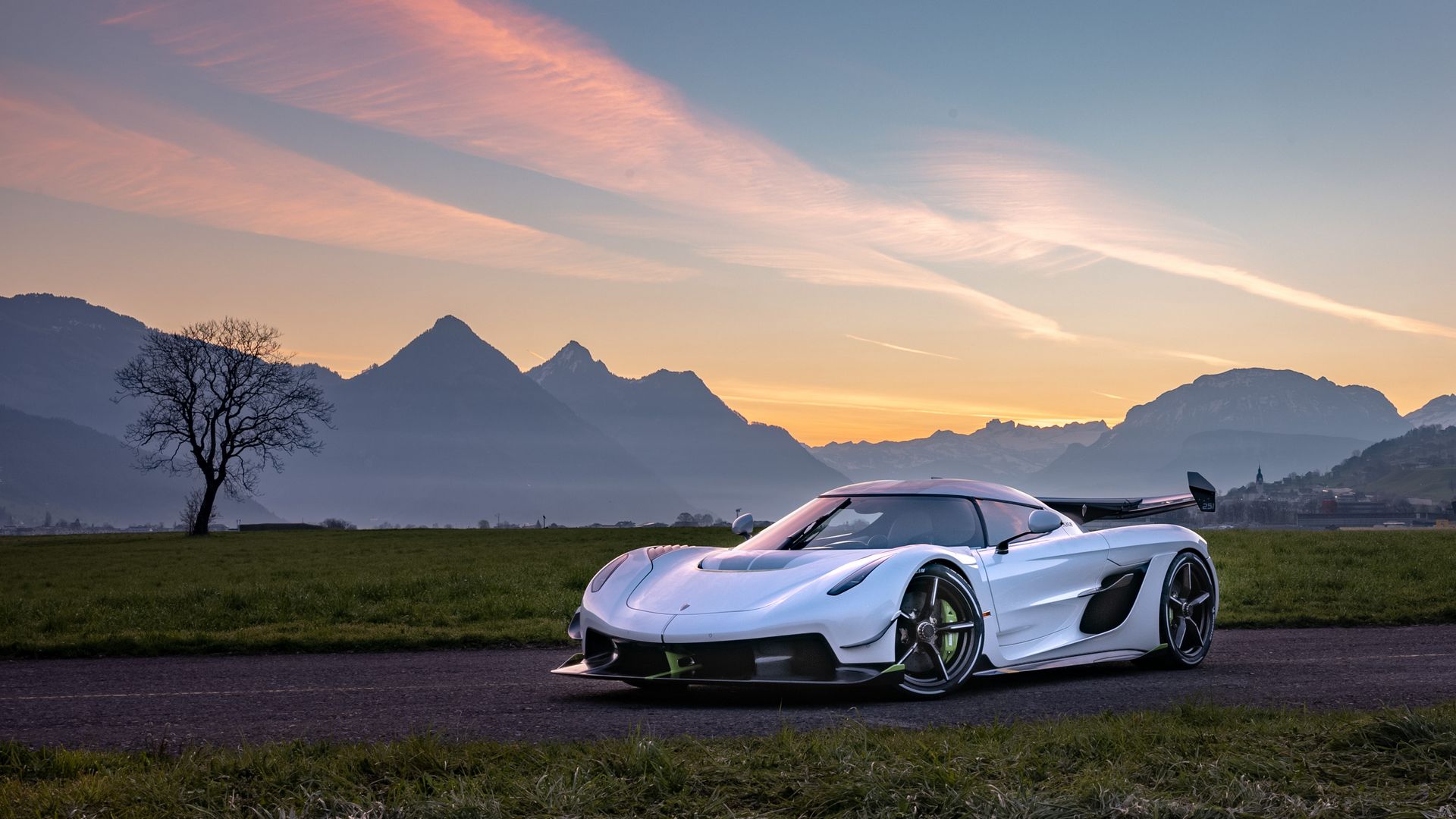 A frontal side view of a Koenigsegg Jesko, in front of a rugged landscape.