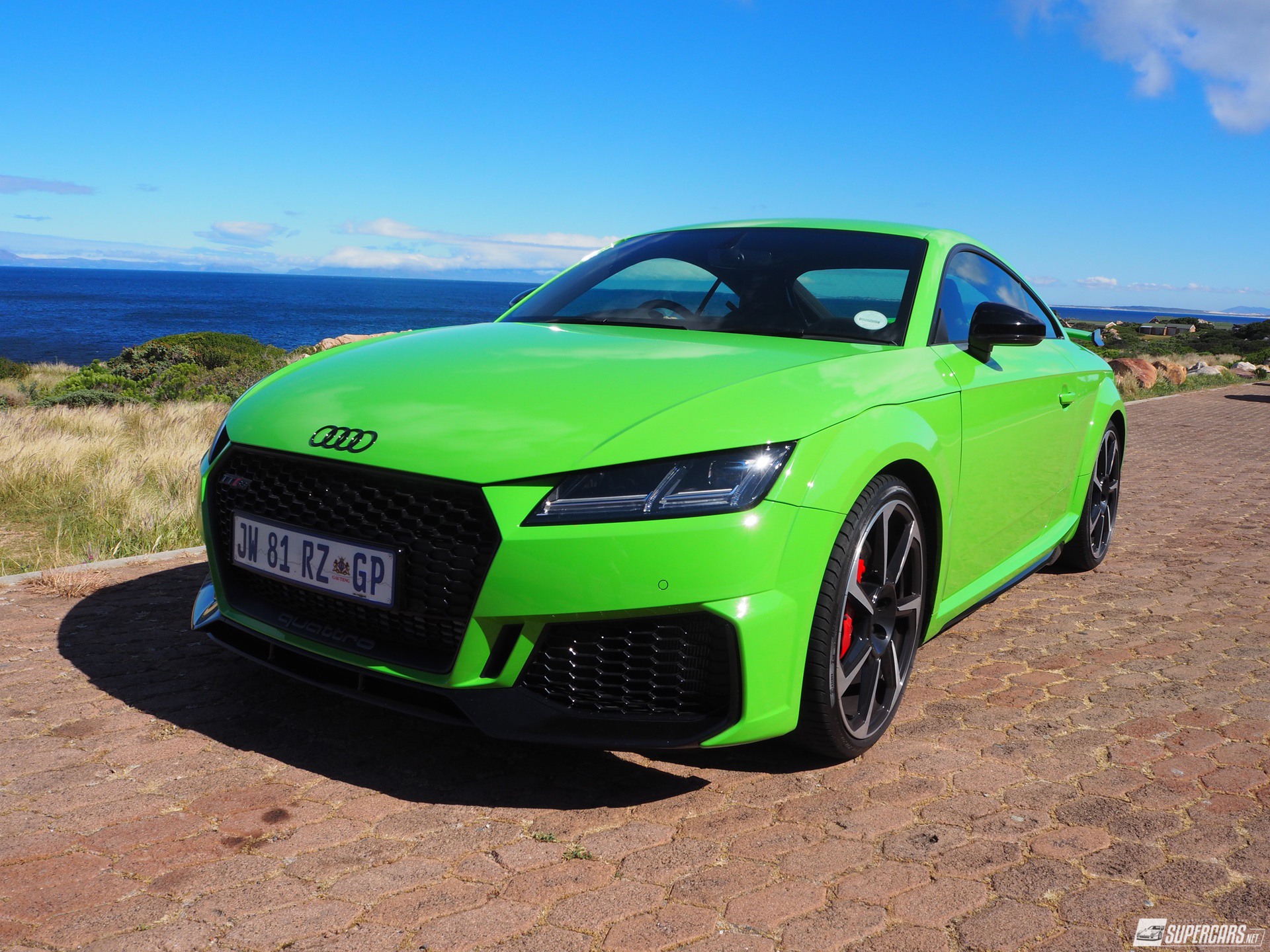 Green 2022 Audi TT RS on cobblestone street near ocean