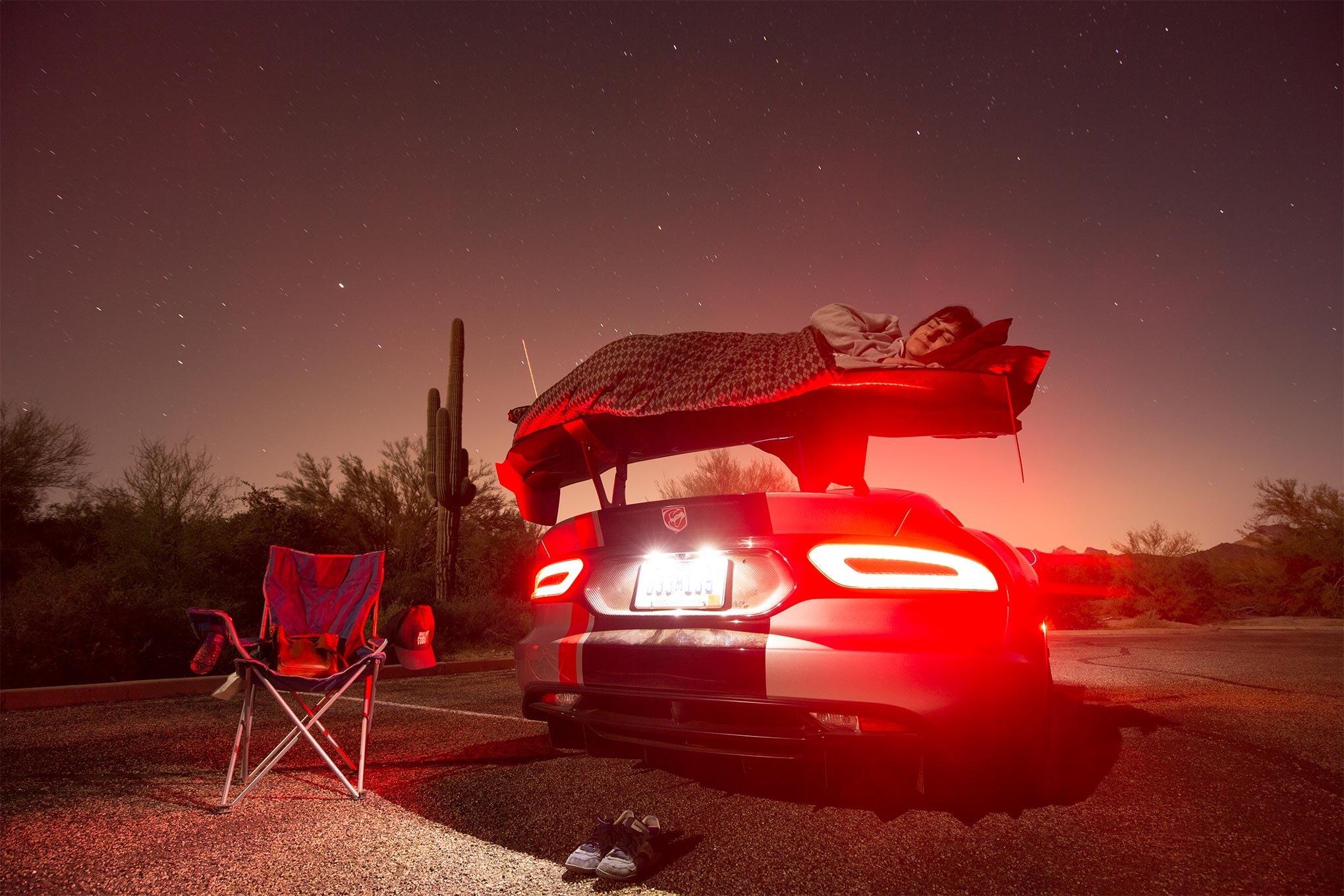 Driver in blanket lying on spoiler of 2016 Dodge Viper ACR and sleeping under stars
