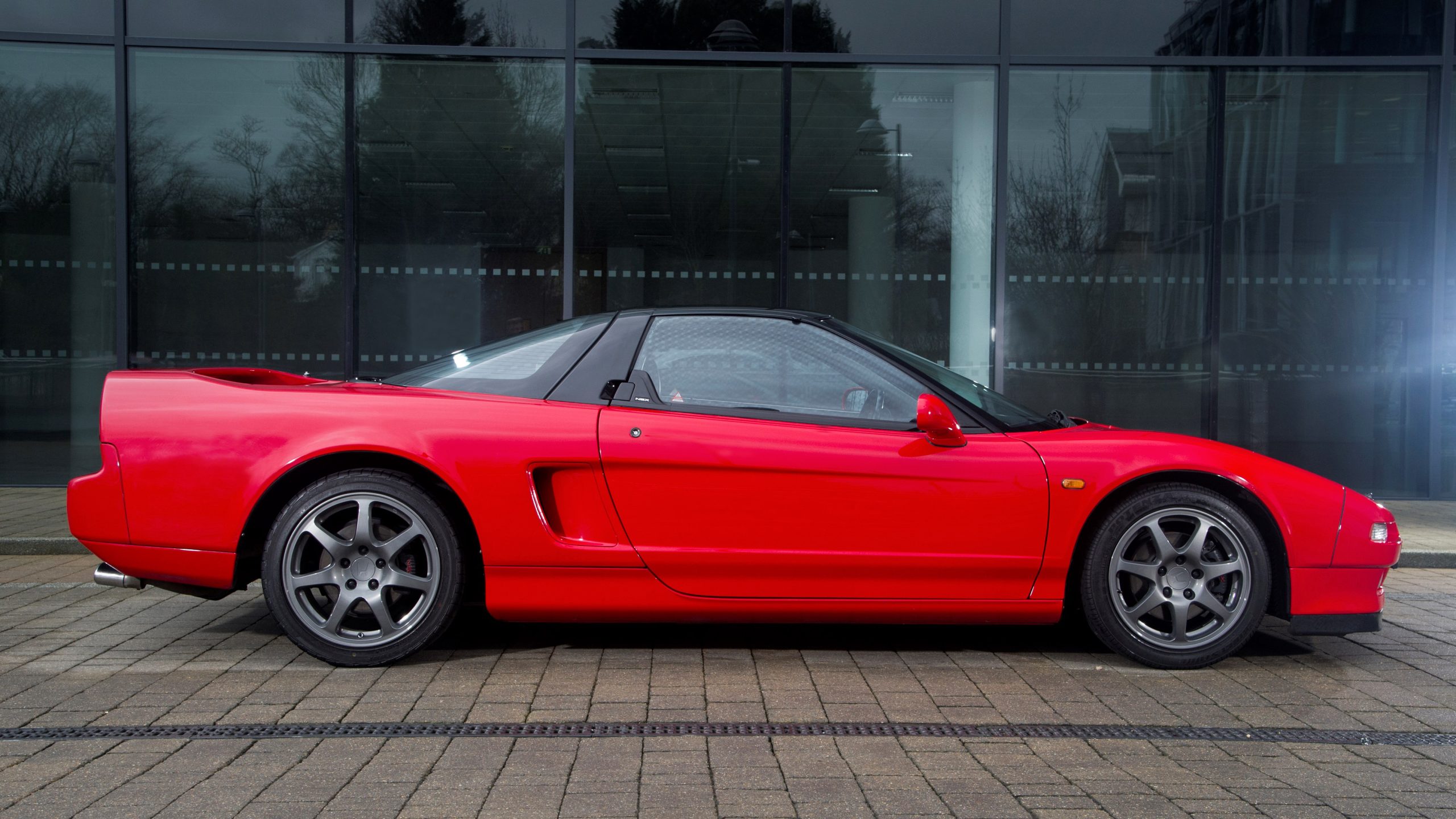 Bright red 1991 Honda NSX sitting on cobblestones outside building