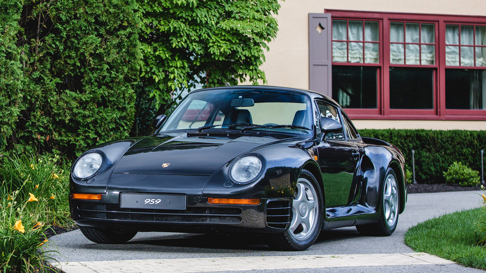 Black Porsche 959 sitting in driveway outside house