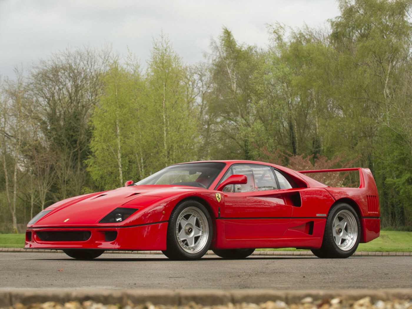 Red Ferrari F40 on road with trees behind