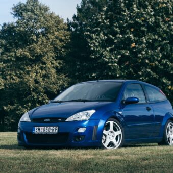 Blue Ford Focus RS on grassy field with trees in background