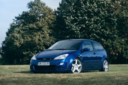 Blue Ford Focus RS on grassy field with trees in background