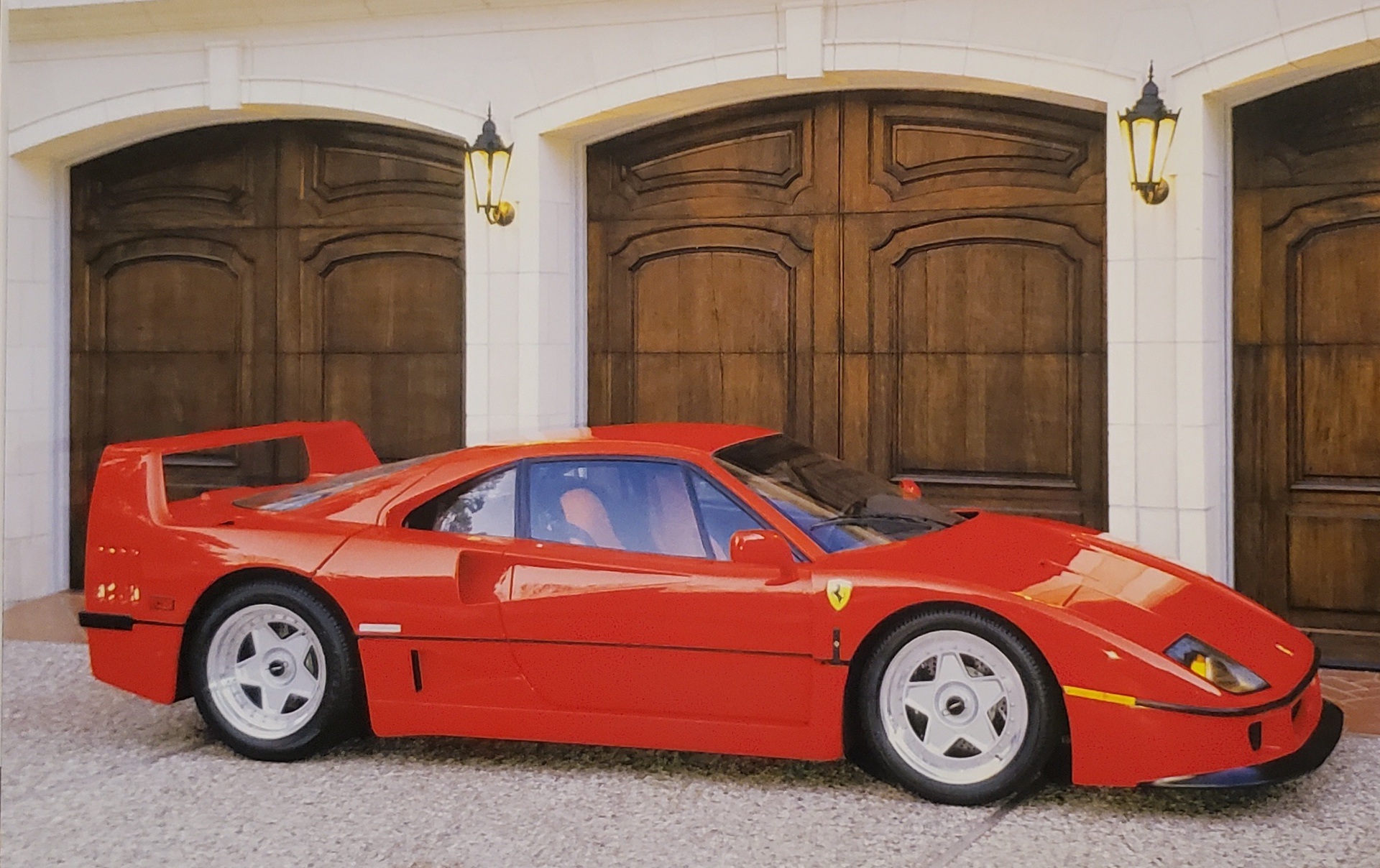 Red Ferrari F40 parked outside manor house