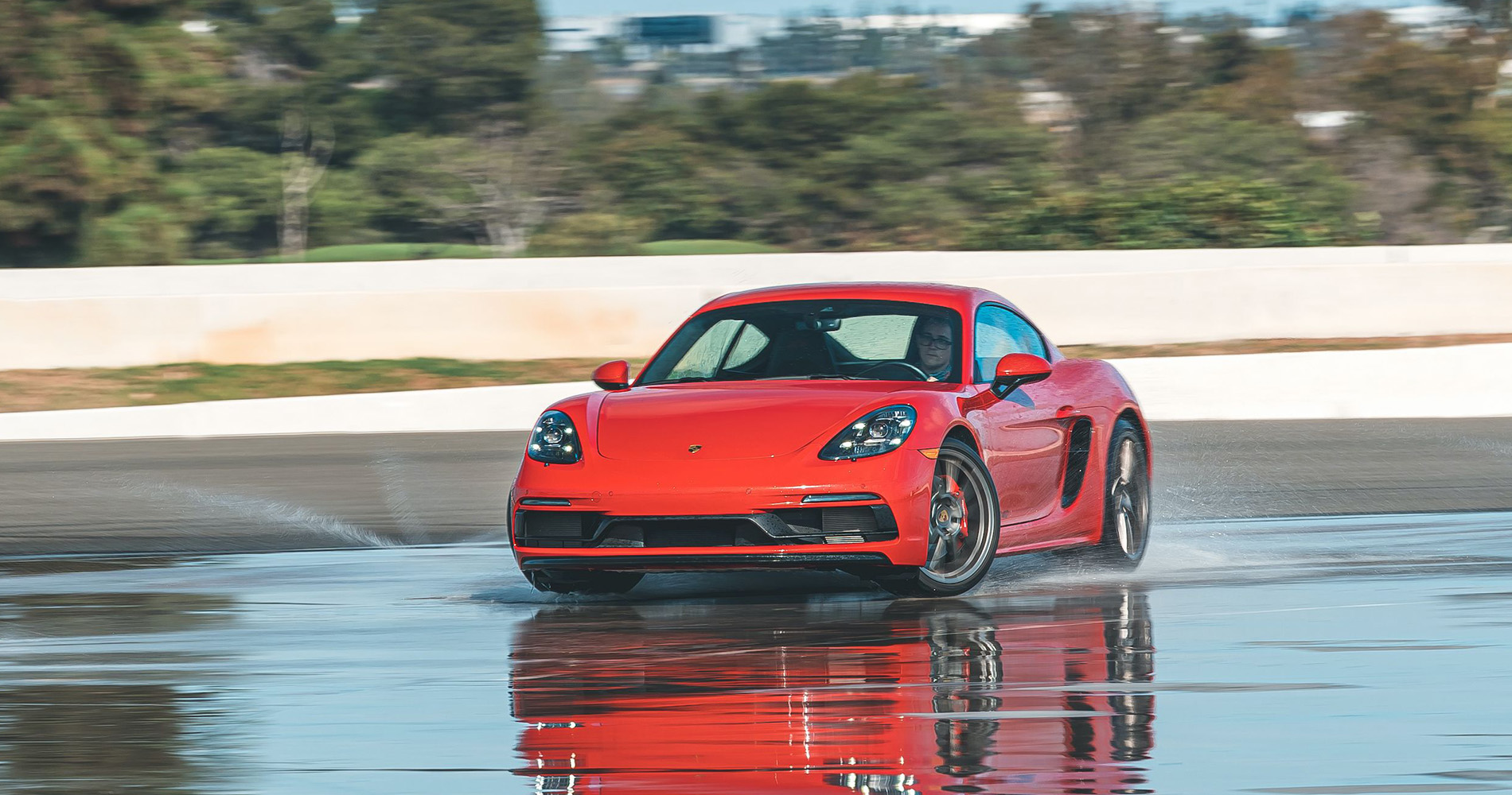 Red Porsche 718 Cayman GTS sliding on a wet track