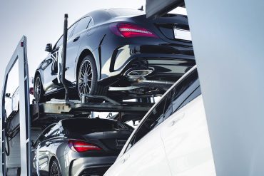 Mercedes Benz vehicles being transported on a car carrier truck.