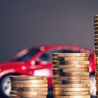 Coins stacked in front of a red car