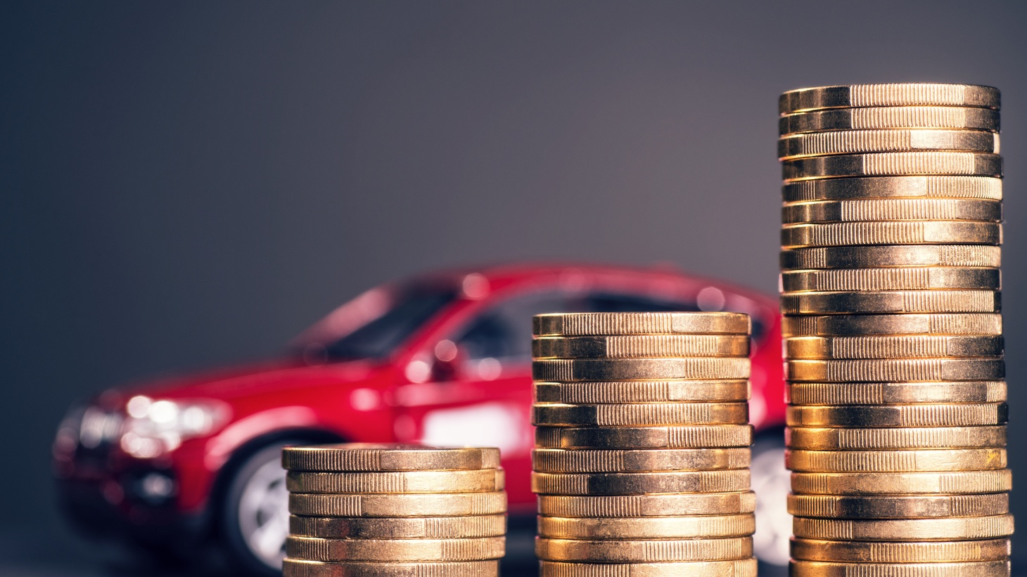 Coins stacked in front of a red car