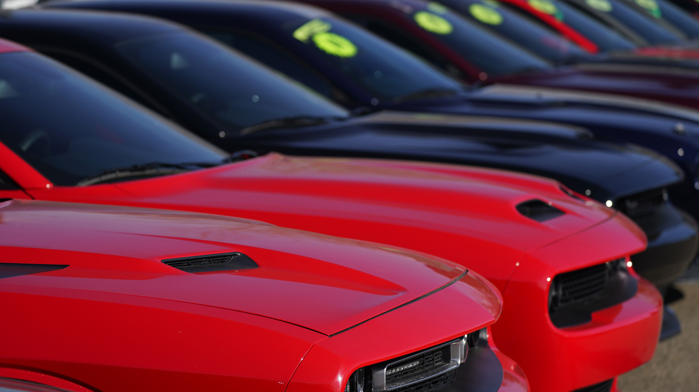 A long line of used Challengers sits at a Dodge dealership 