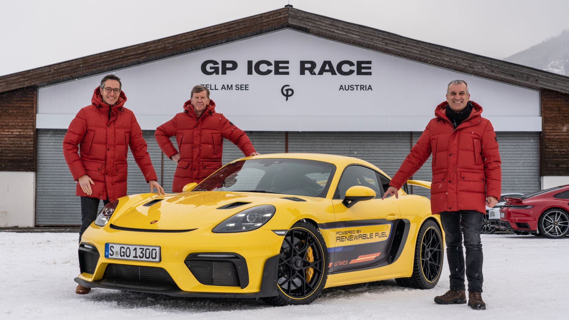 Three men standing near yellow Porsche 718 Cayman GT4 RS Clubsport race car outside