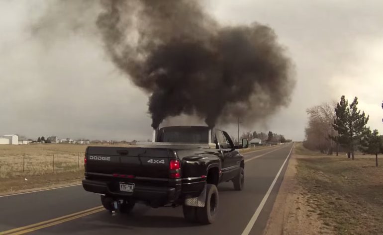 A truck with smoke coming out of its exhaust pipes