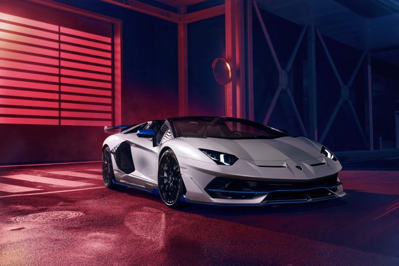 Front angled shot of a silver Lamborghini Aventador SVJ Roadster Xago Edition against a darkened background.