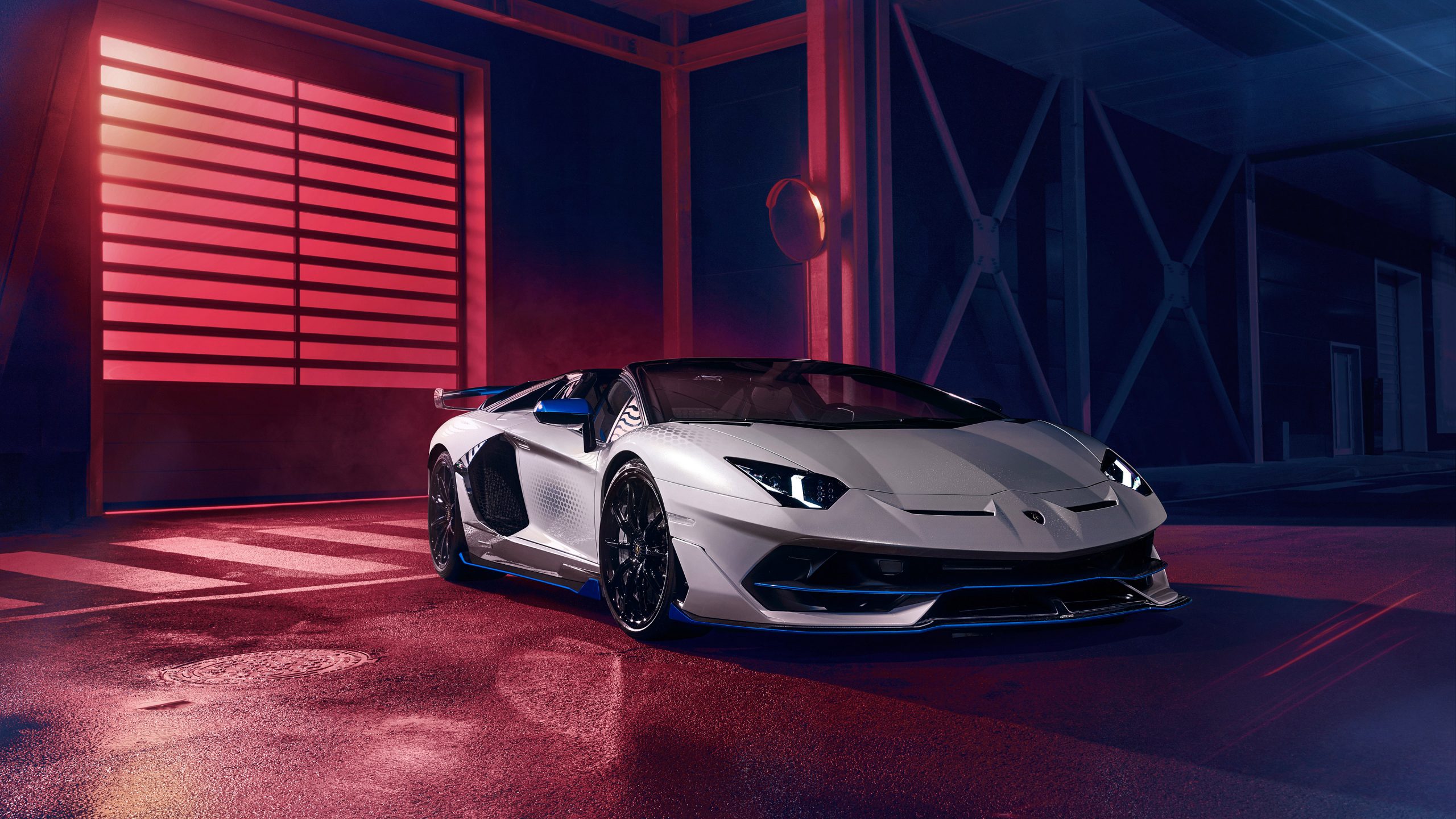 Front angled shot of a silver Lamborghini Aventador SVJ Roadster Xago Edition against a darkened background.