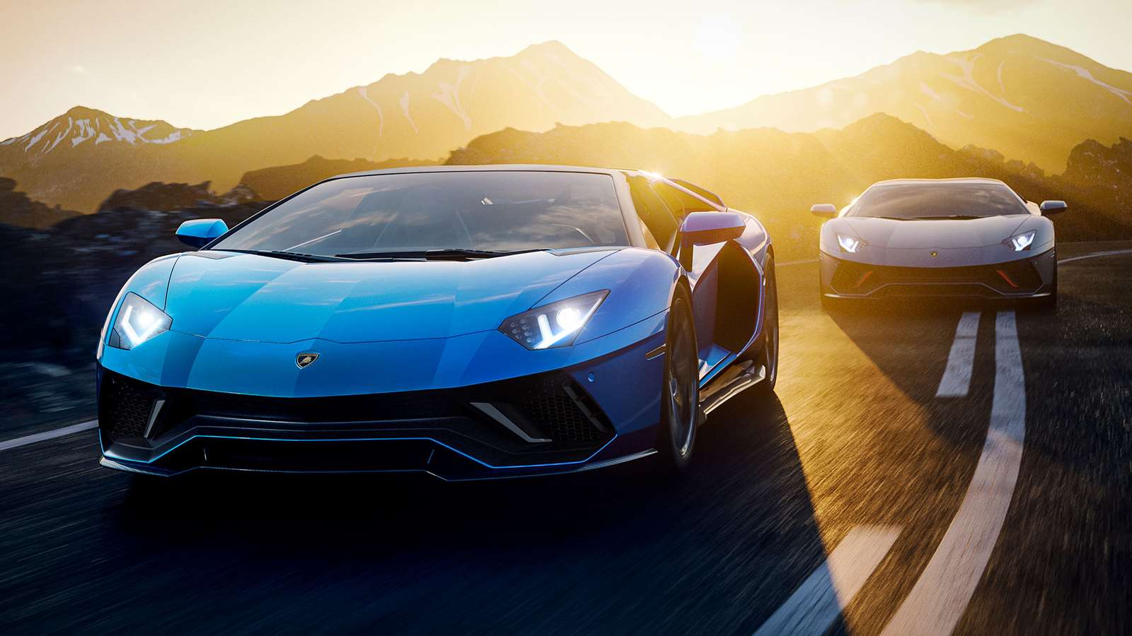 Front view of a blue Lamborghini Aventador Ultimae Roadster in the foreground and grey Aventador Ultimae coupe in the background