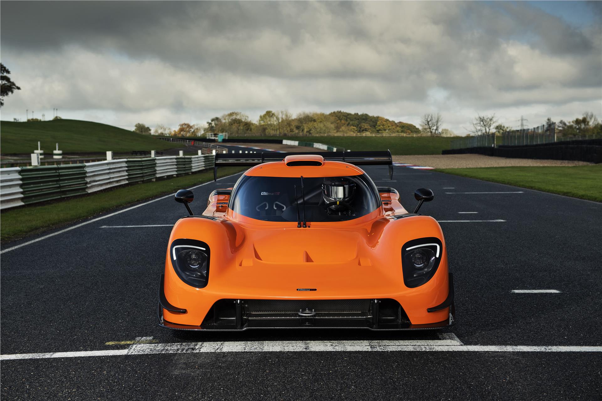 Image showing the frontal view of an orange Ultima RS on a race track.