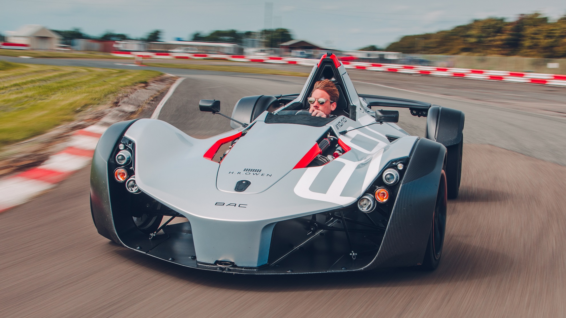 Front-angled shot of a gray BAC Mono going around a race track.