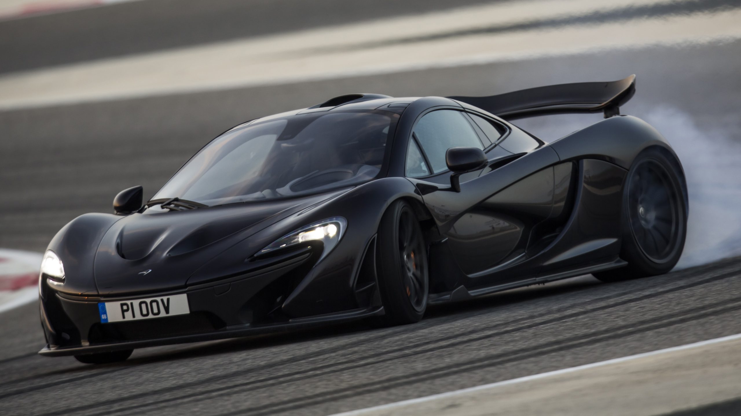 front-angled shot of a black McLaren P1 drifting around a racetrack.
