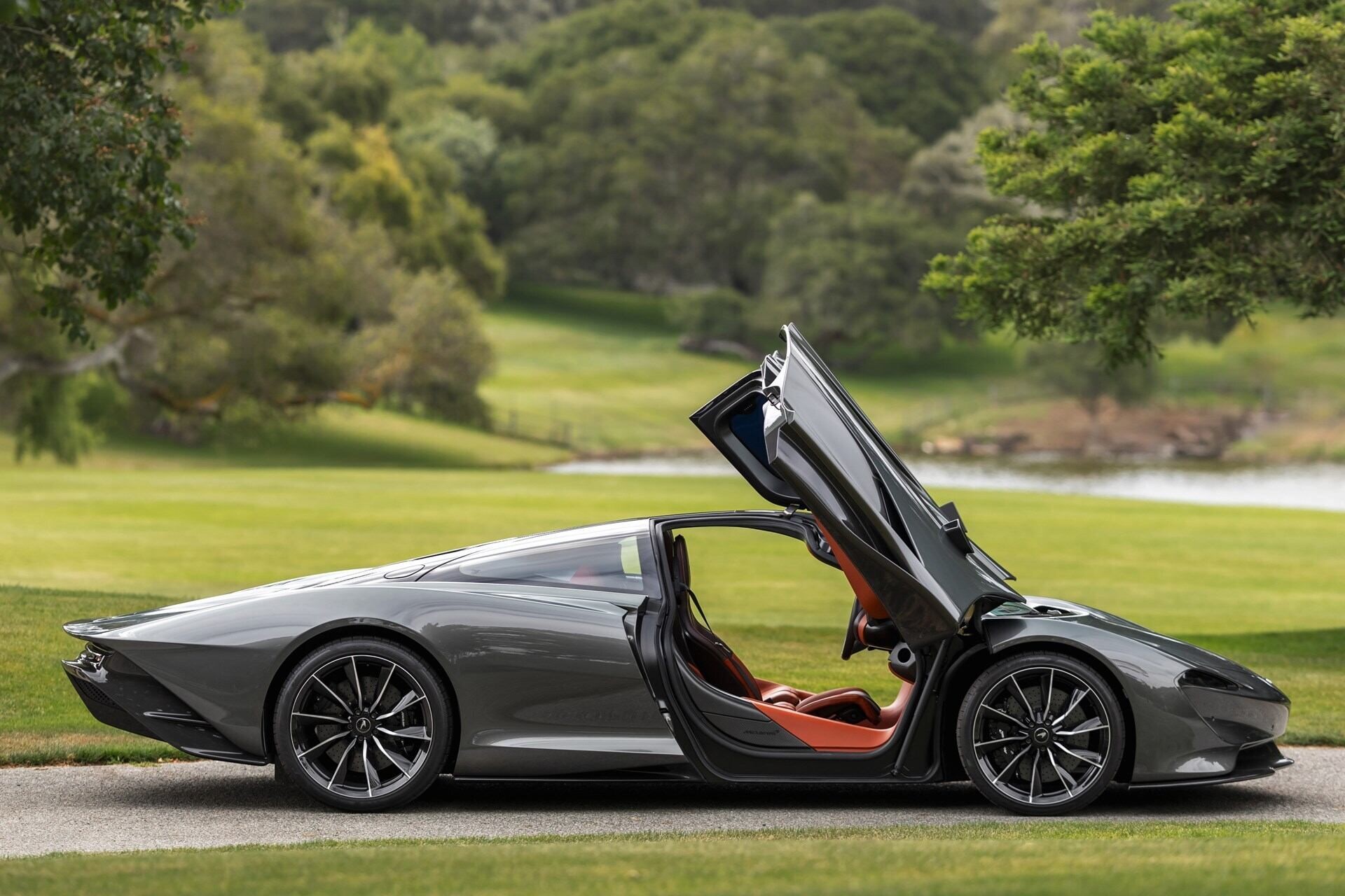 Side profile of a 2020 Grey McLaren Speedtail. with butterfly doors open.