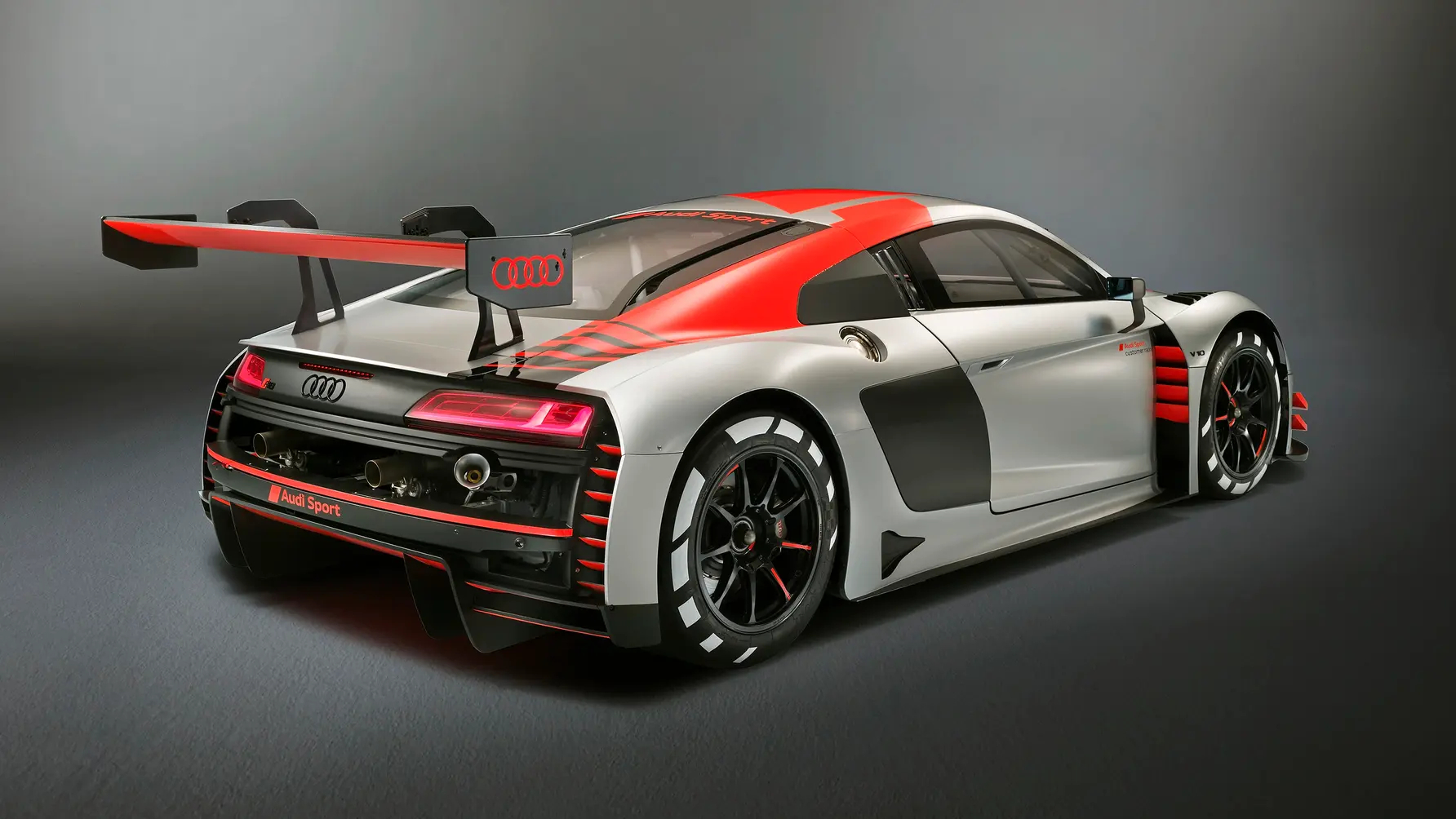 Rear-angled view of an Audi R8 LMS GT3 race car finished in red, white and black livery.