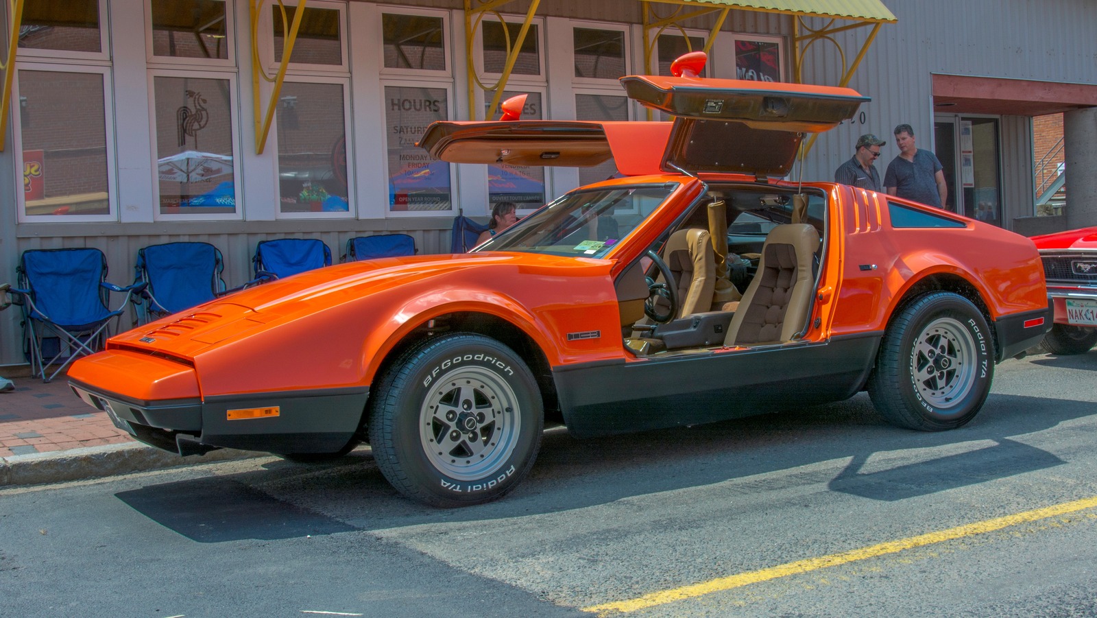 Front-angled image of an orange Bricklin SV-1 with its butterfly doors open.
