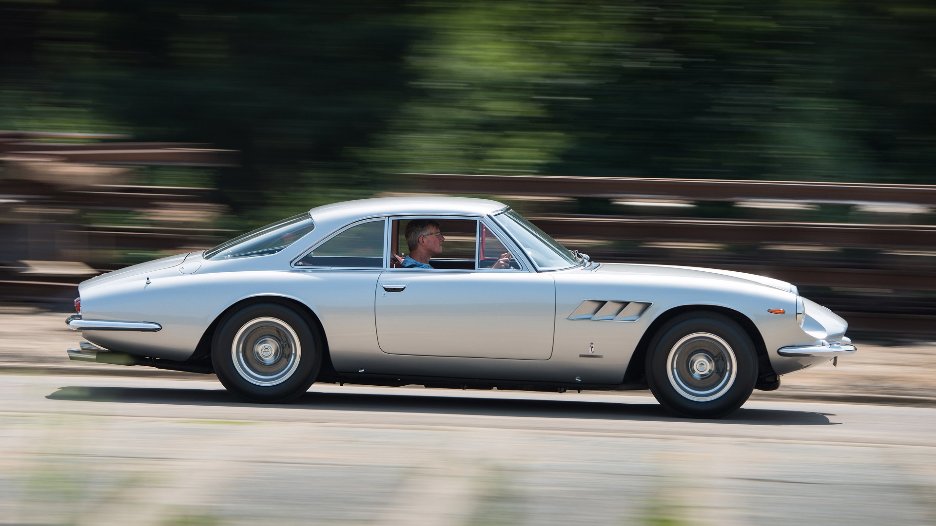 Image showing the side profile of a silver Ferrari 500 Superfast in a rolling shot.