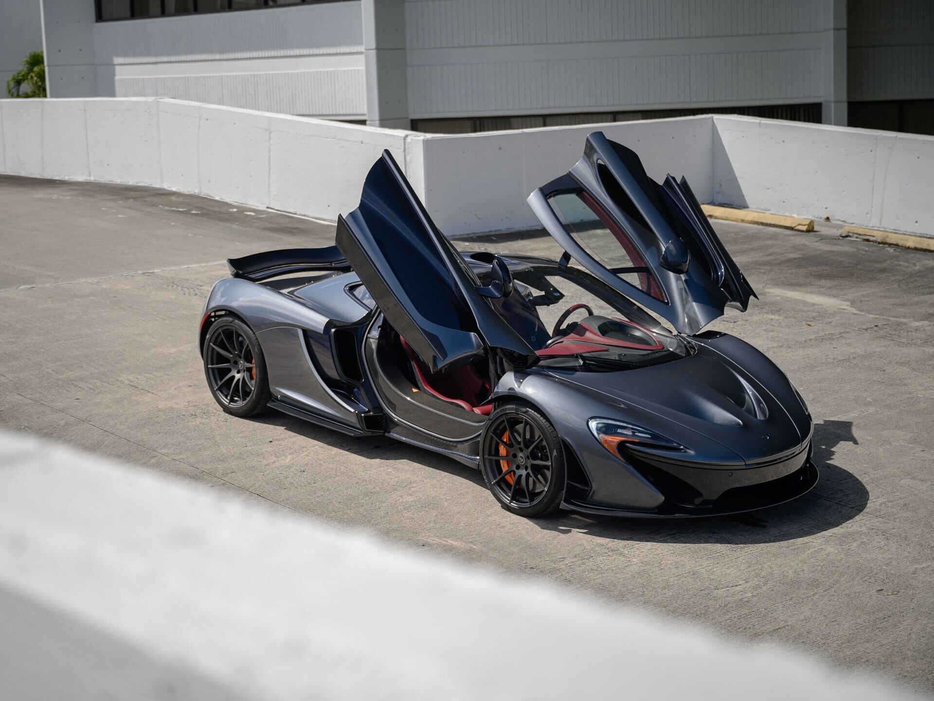 front angled view of a grey 2015 McLaren P1 with butterfly doors open.