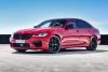 Front-angled view of a 2021 BMW M5 Competition finished in a bold red colour with orange undertones.