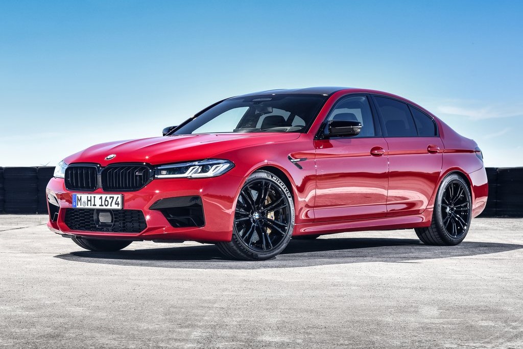 Front-angled view of a 2021 BMW M5 Competition finished in a bold red colour with orange undertones.