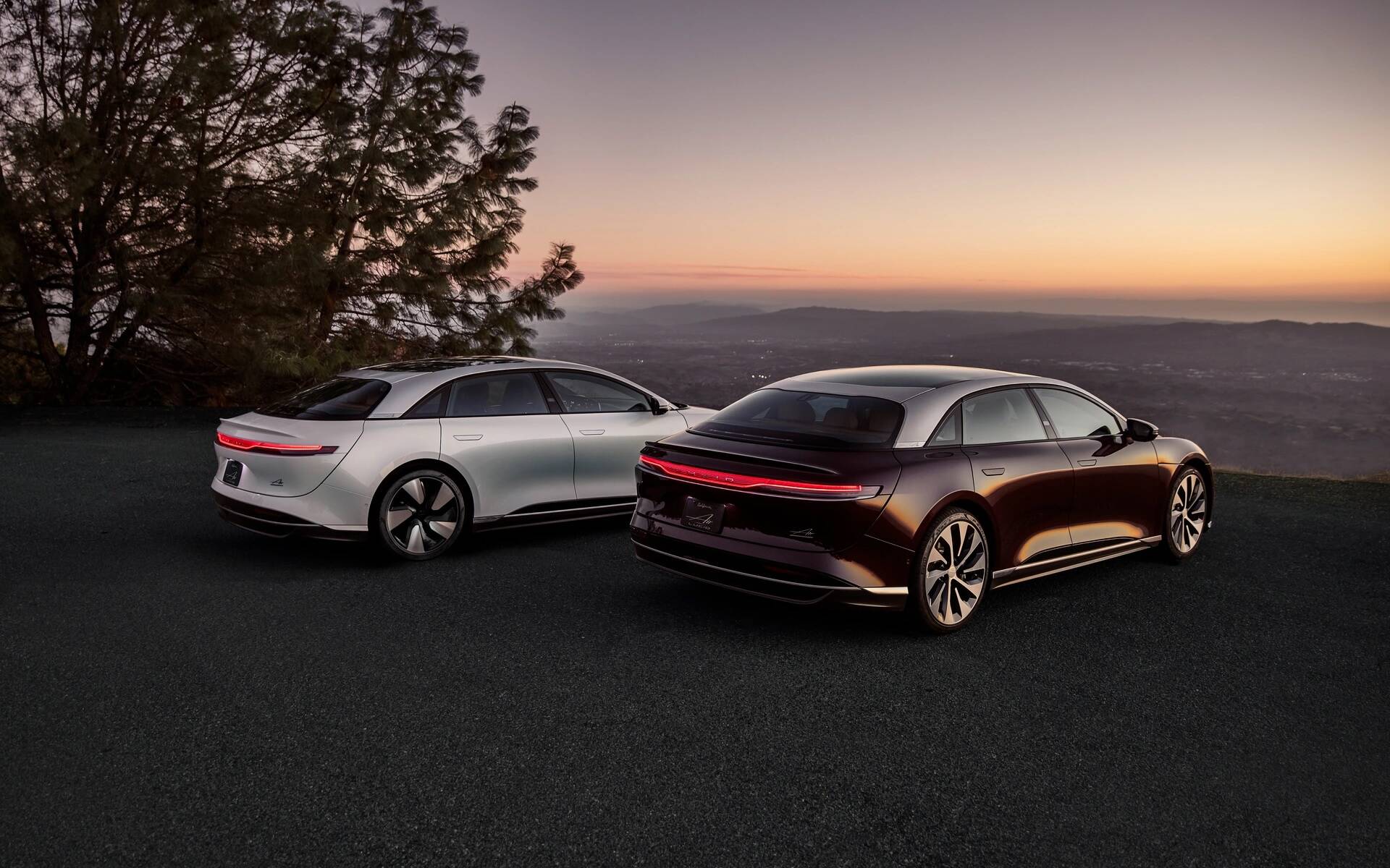 Rear-angled image of two Lucid Air performance luxury sedans.
