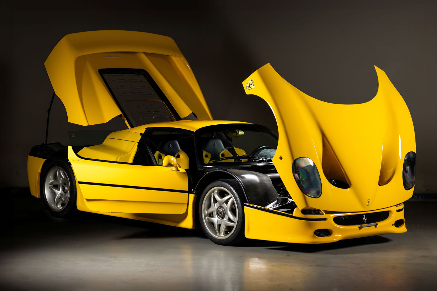 Front angled view of a yellow Ferrari F50 with all doors and hood opened