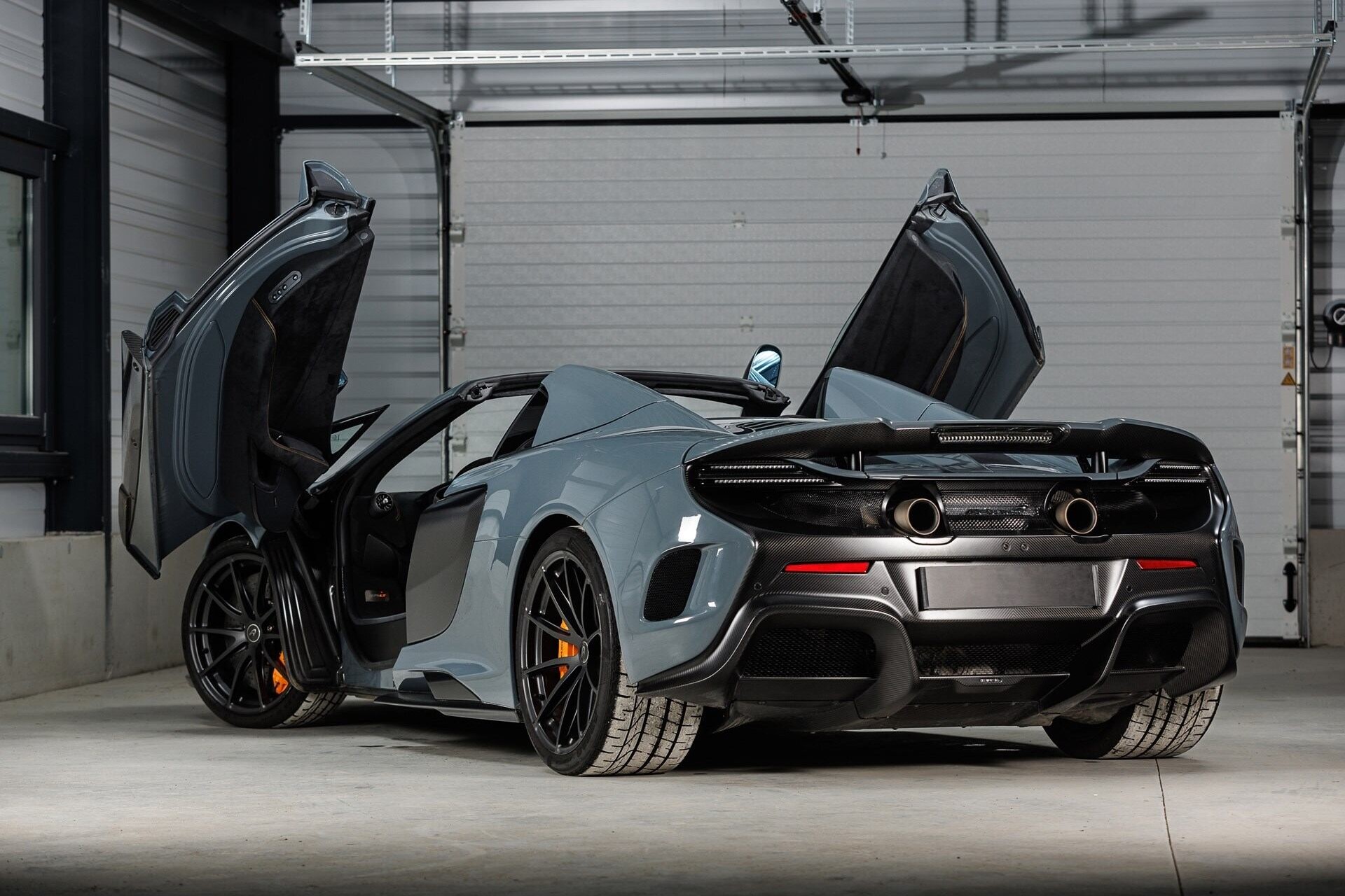 Rear angled view of a 2017 Chicane Grey McLaren 675LT with doors open