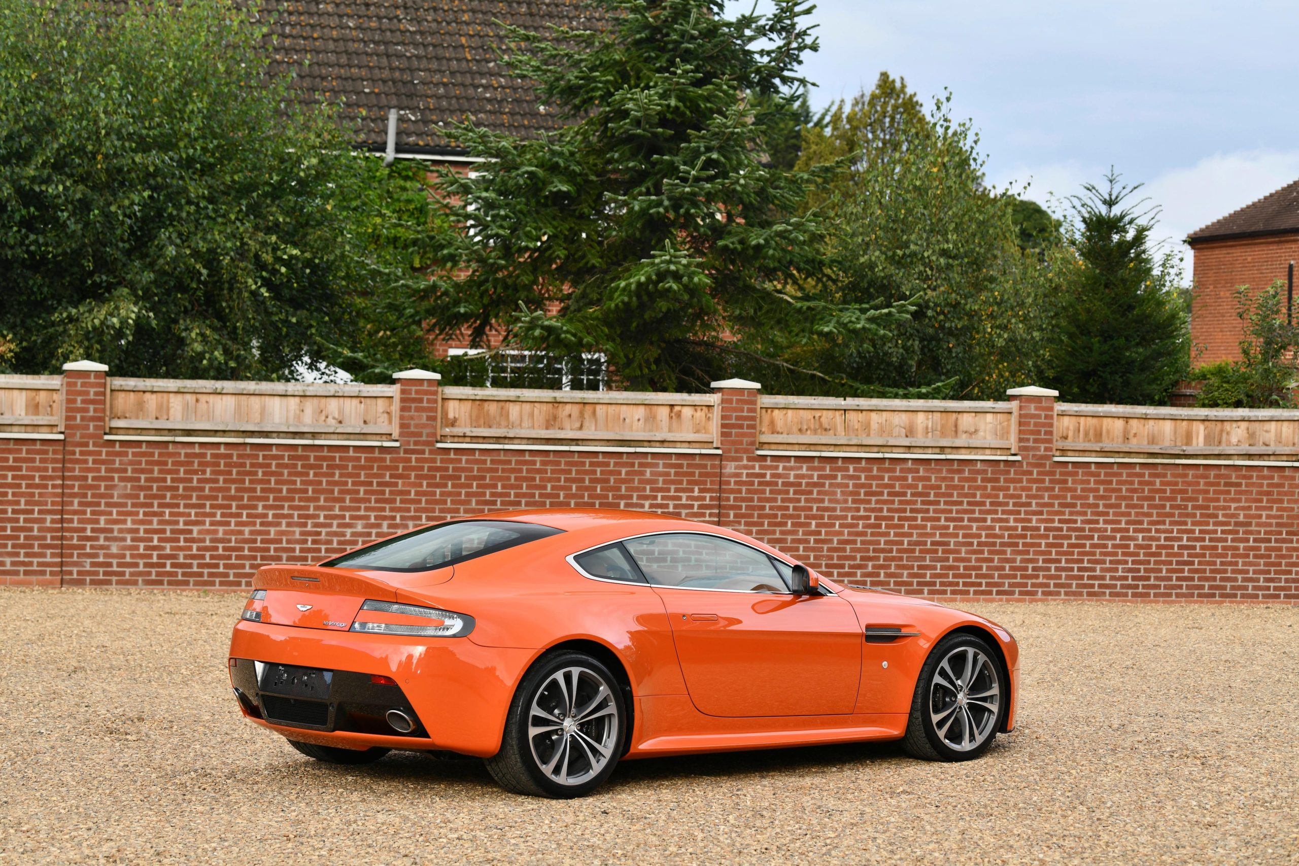rear angled profile of an orange Aston Martin V12 Vantage