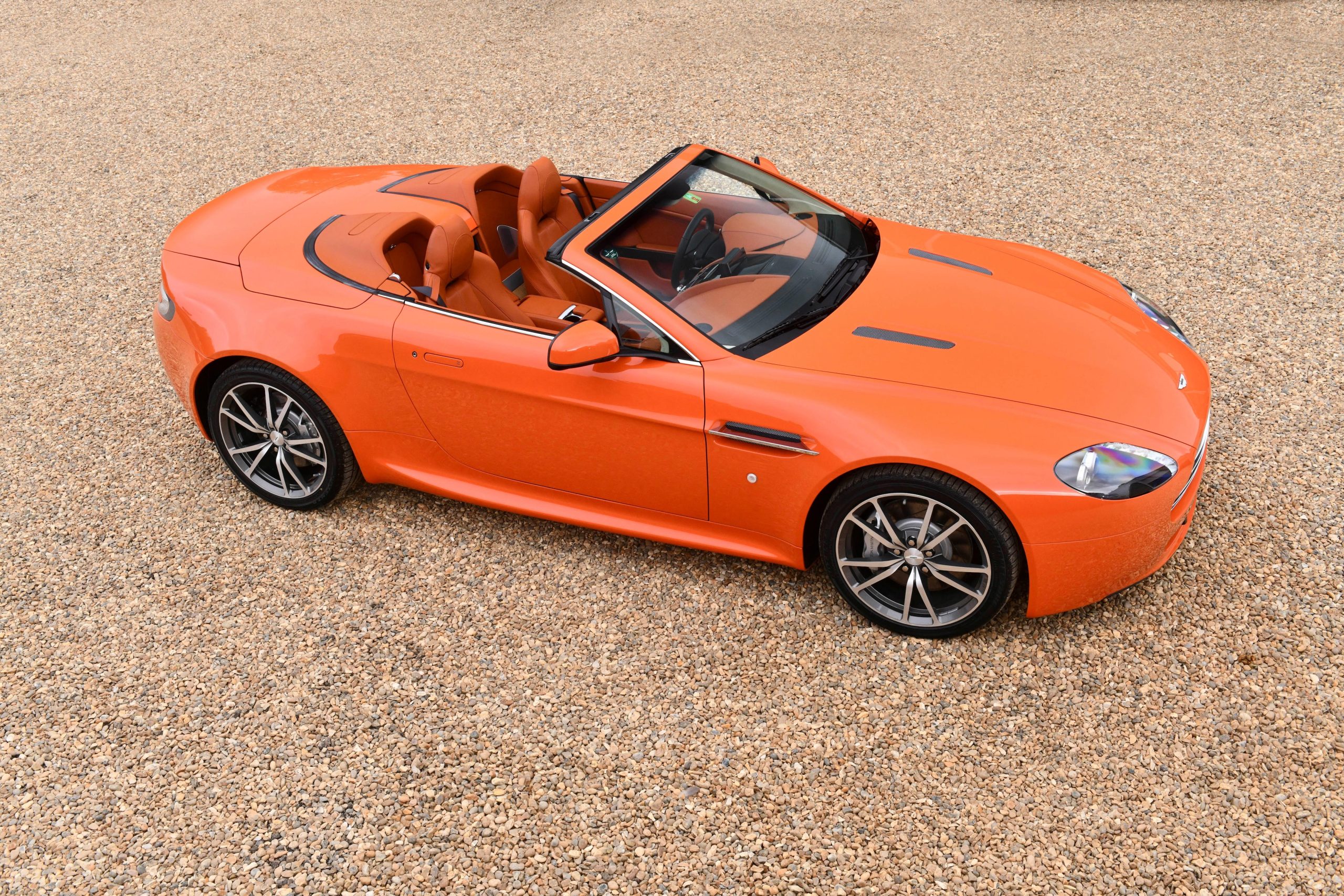 Angled aerial view of an orange Aston Martin V8 Vantage