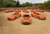 A fleet of eight orange Aston Martin vehicles