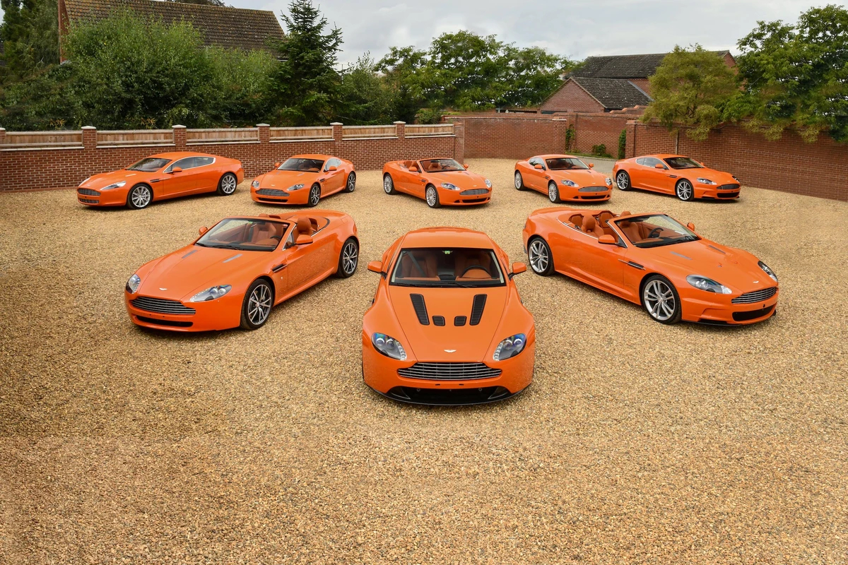 A fleet of eight orange Aston Martin vehicles