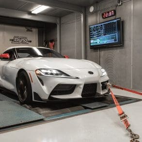 Three-quarter front view of a 2020 white Toyota Supra being tested on a dyno