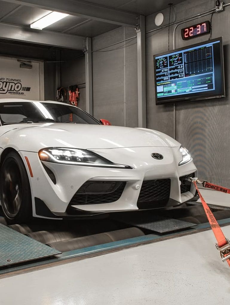 Three-quarter front view of a 2020 white Toyota Supra being tested on a dyno
